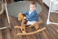 Baby girl playing on wooden rocking horse. Childhood, game at home concept