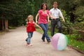 Girl plays with big ball in park with parents Royalty Free Stock Photo