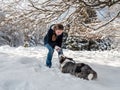 A girl plays with a corgi dog in a snowy forest. Sunlight. Winter`s tale