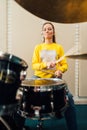 The girl plays the drum kit diligently.