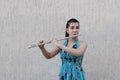 Girl plays the flute in front of a gray background Royalty Free Stock Photo