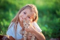 The girl plays with a ginger kitten on the street in the grass. Country girl playing with a cat