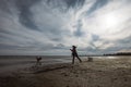 A girl plays with her dogs on the beach