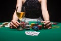 Girl plays poker in a casino, with chips, dollars, and wine. Concept of a gaming business