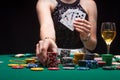 Girl plays poker in a casino, with chips, dollars, and wine. Concept of a gaming business