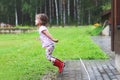 Girl plays in rainy weather Child jumping in puddle and mud in the rain. Royalty Free Stock Photo