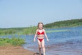 A girl plays on a sandy beach on the shore of a lake in the summer heat. Royalty Free Stock Photo