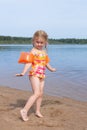 A girl plays on a sandy beach on the shore of a lake in the summer heat. Royalty Free Stock Photo