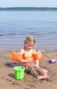 A girl plays on a sandy beach on the shore of a lake in the summer heat. Royalty Free Stock Photo