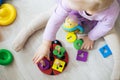 girl plays toys in living room. Montessori wooden toy folded pyramid. Circle, quadra, triangle, rectangle wooden elements of