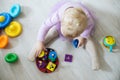 girl plays toys in living room. Montessori wooden toy folded pyramid. Circle, quadra, triangle, rectangle wooden elements of