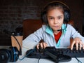 A girl plays a video game while sitting in front of a monitor. She carefully looks at the screen. Royalty Free Stock Photo