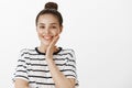 Girl is pleased with result of beauity therapy. Charming healthy european woman in striped t-shirt, touching cheek Royalty Free Stock Photo