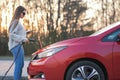 Girl is plugging electric vehicle for charging car battery at parking. Plugged charging cable electric vehicle. EV