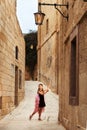 A girl on the pointe shoes in a princess dress dancing walks in the narrow streets of the ancient city