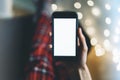 Girl pointing finger a black smartphone with a empty blank screen monitor on the background bokeh light in a homely atmosphere