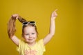 Girl pointing with finger at copy space on yellow background