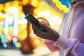 Girl pointing finger on screen smartphone on background bokeh light in night atmospheric city illumination in evening street defoc