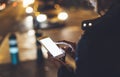 Girl pointing finger on screen smartphone on background bokeh light in night atmospheric city street, blogger hipster girl using