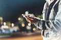 Girl pointing finger on screen smartphone on background illumination bokeh color light in night atmospheric city, hipster using in Royalty Free Stock Photo