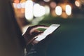 Girl pointing finger on screen smartphone on background illumination bokeh color light in night atmospheric city, hipster using in Royalty Free Stock Photo