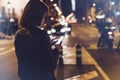 Girl pointing finger on screen smartphone on background illumination glow bokeh light in night atmospheric christmas city, hipster Royalty Free Stock Photo