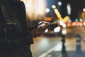 Girl pointing finger on screen smartphone on background illumination glow bokeh light in night atmospheric christmas city, hipster Royalty Free Stock Photo