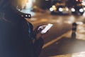 Girl pointing finger on screen smartphone on background illumination glow bokeh light in night atmospheric christmas city, hipster Royalty Free Stock Photo