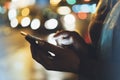 Girl pointing finger on screen smartphone on background illumination glow bokeh light in night atmospheric christmas city, hipster Royalty Free Stock Photo