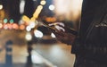 Girl pointing finger on screen smartphone on background illumination glow bokeh light in night atmospheric christmas city, hipster Royalty Free Stock Photo