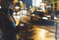 Girl pointing finger on screen smartphone on background illumination glow bokeh light in night atmospheric christmas city, smiling Royalty Free Stock Photo