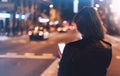 Girl pointing finger on screen smartphone on background illumination glow bokeh light in night atmospheric city, hipster girl usin