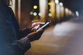 Girl pointing finger on screen smartphone on background illumination glow bokeh light in night atmospheric city, hipster using Royalty Free Stock Photo