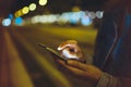 Girl pointing finger on screen smartphone on background illumination glow bokeh light in night atmospheric city, hipster using Royalty Free Stock Photo