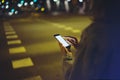 Girl pointing finger on screen smartphone on background illumination glow bokeh light in night atmospheric city, hipster using Royalty Free Stock Photo