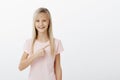 Girl pointing at her teacher who she likes. Portrait of pleased happy young child with blonde hair, pointing at upper