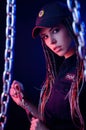 A girl in a police uniform with dreadlocks in neon light with chains and handcuffs English translation the police