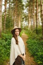 A girl in a poncho and a hat in forest