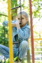 Girl pondered climbed the hanging ladder in the playground