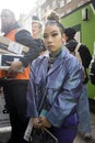 Girl with a ponytail in a blue silk shiny jacket and trousers with pockets, jewelry with a succulent in a pot posing