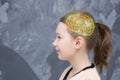 Girl with a ponytail in profile with a drawing of a golden brain