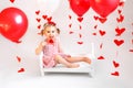 Girl is sitting on a small crib with a large red heart-shaped lollipop Royalty Free Stock Photo