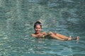 Girl in the pool outdoors. The salt water of the pool holds it on the surface of the water. Smiling, sunglasses on his head