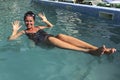 Girl in the pool outdoors. The salt water of the pool holds it on the surface of the water. Smiling, sunglasses on his head