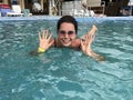 Girl in the pool outdoors. The salt water of the pool holds it on the surface of the water. Smiling, sunglasses on his head