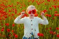 Girl with poppies eyes. Child girl resting in a poppies spring meadow. Kids play in the field with poppy flowers. Little