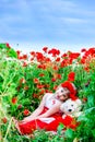 Girl in poppy field sitting with a teddy bear