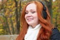 Girl portrait, listen music on audio player with headphones, sit on bench in city park, autumn season, yellow trees and fallen lea Royalty Free Stock Photo