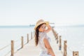 Girl pose at sea pier in straw hat and sunglasses. Woman in swimsuit on tropical beach on sunny blue sky. Summer vacation. Re