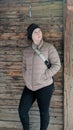 Girl posing in front of wood wall in Winter wearing a jacket.